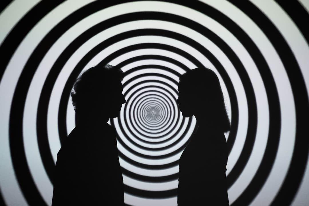 silhouette of 2 person standing in front of white and black stripe wall